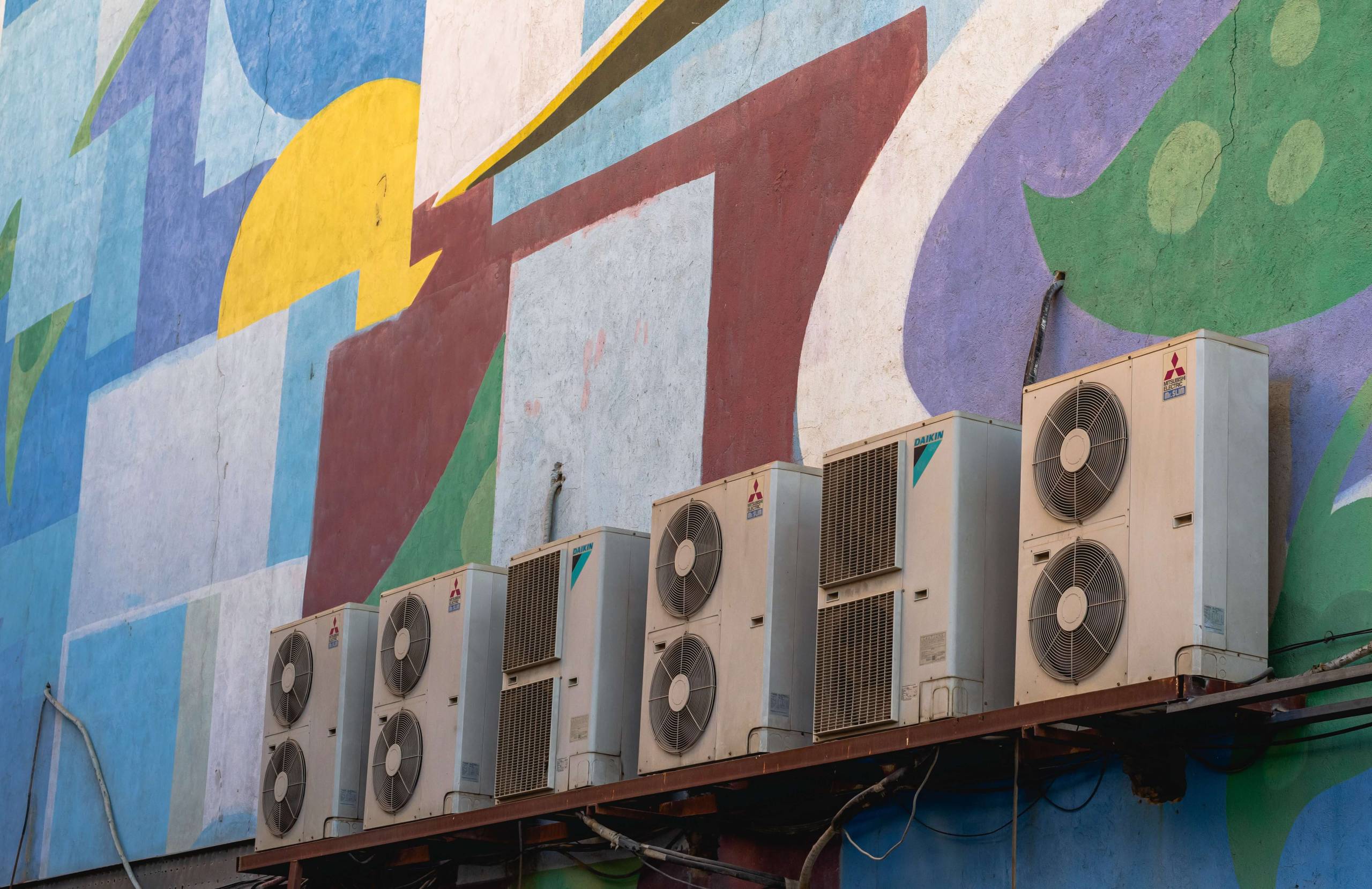 Air conditioner units on a colorful outdoor wall as the cover for a blog post about hvac keywords